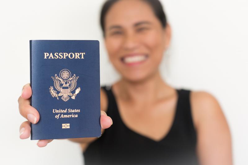 a happy immigrant woman holds up her US passport