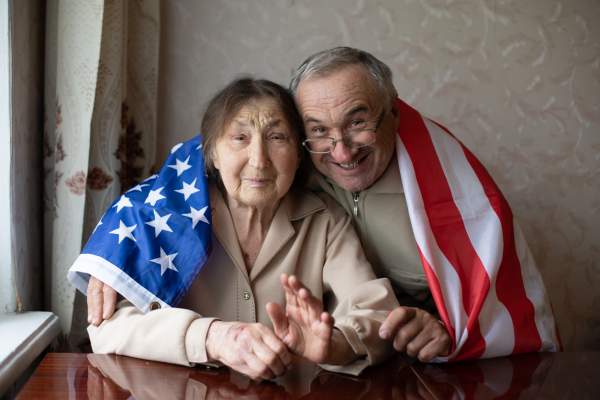 elderly couple with american flag draped over their shoulders