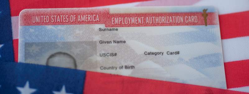 United States of America Employment Authorization Card on a U.S. flag’s surface.