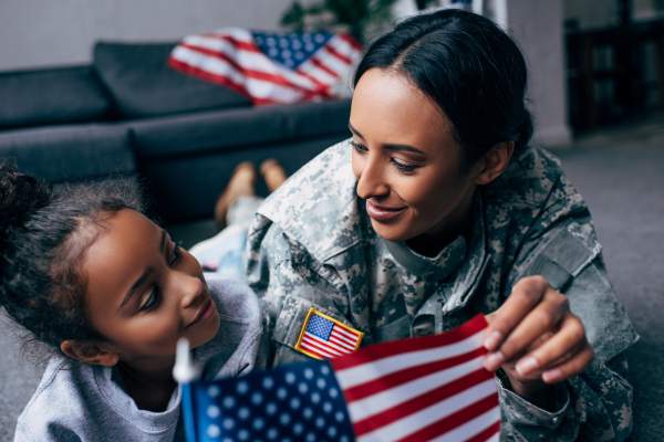 military woman and daughter holding small american flag