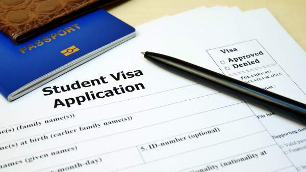 passport and pen on top of student visa application form
