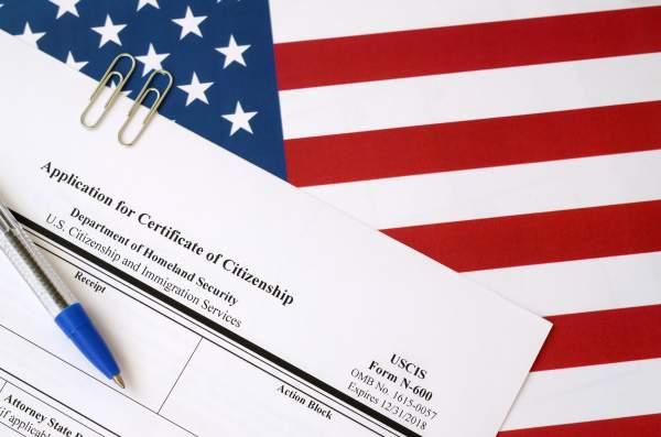 pen atop application for certificate of citizenship with american flag background