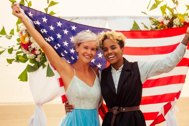 same sex couple takes wedding photos with american flag