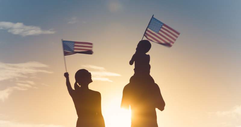 silhouettes of family holding american flags
