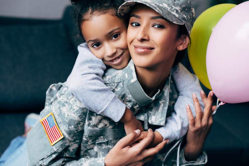 young girl hugs military mother around neck